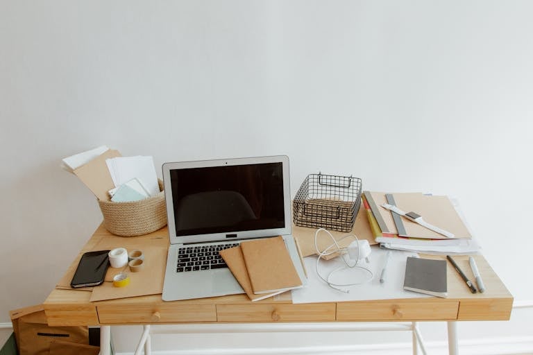 Clean and organized desk with a laptop, notebooks, and office supplies for productivity.
