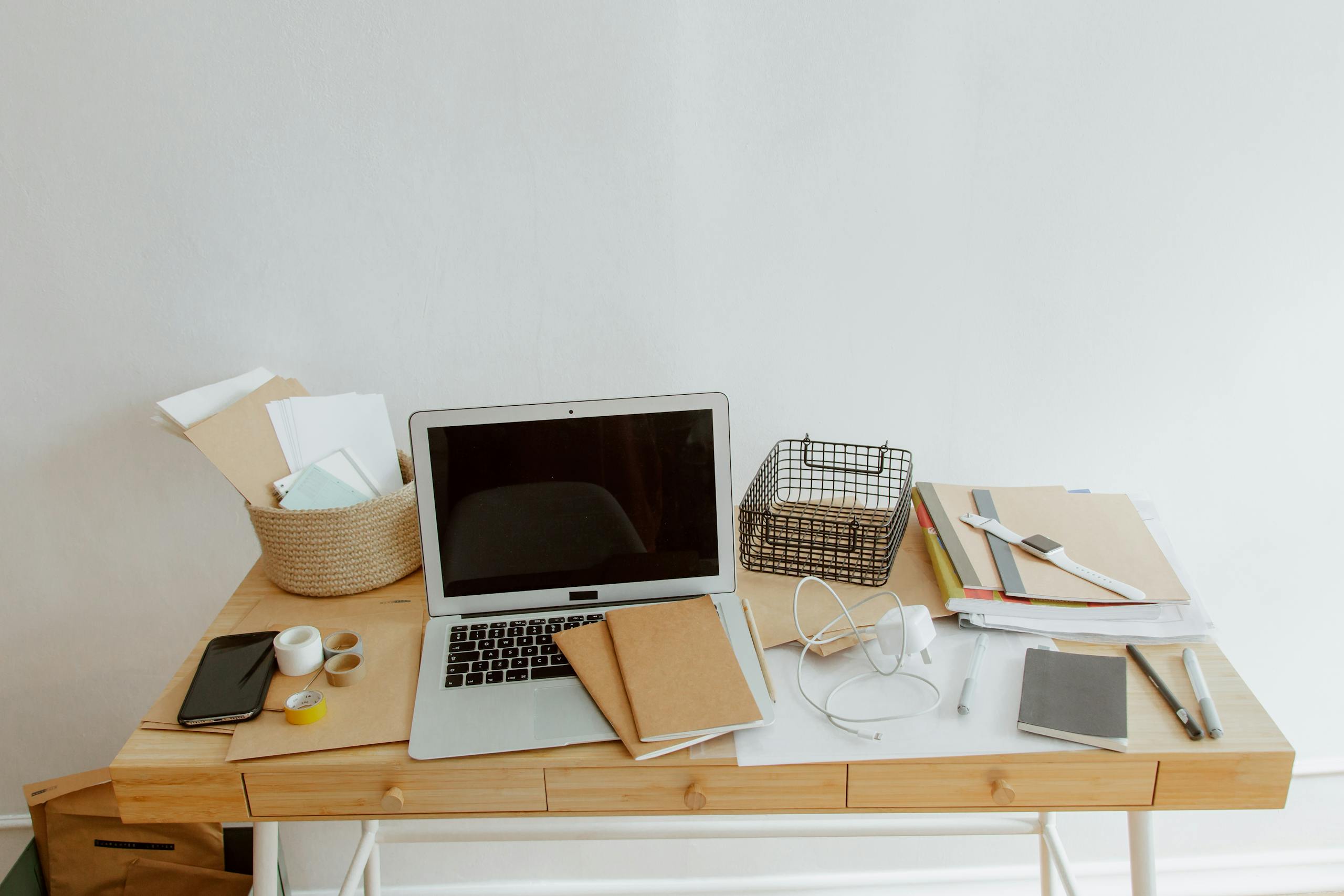 Clean and organized desk with a laptop, notebooks, and office supplies for productivity.